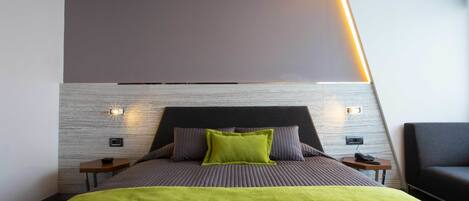 A modern hotel room with a bed, bedside tables, and a nightstand.