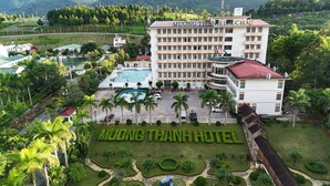 Een hotel met een zwembad, omringd door weelderige begroeiing en palmbomen.