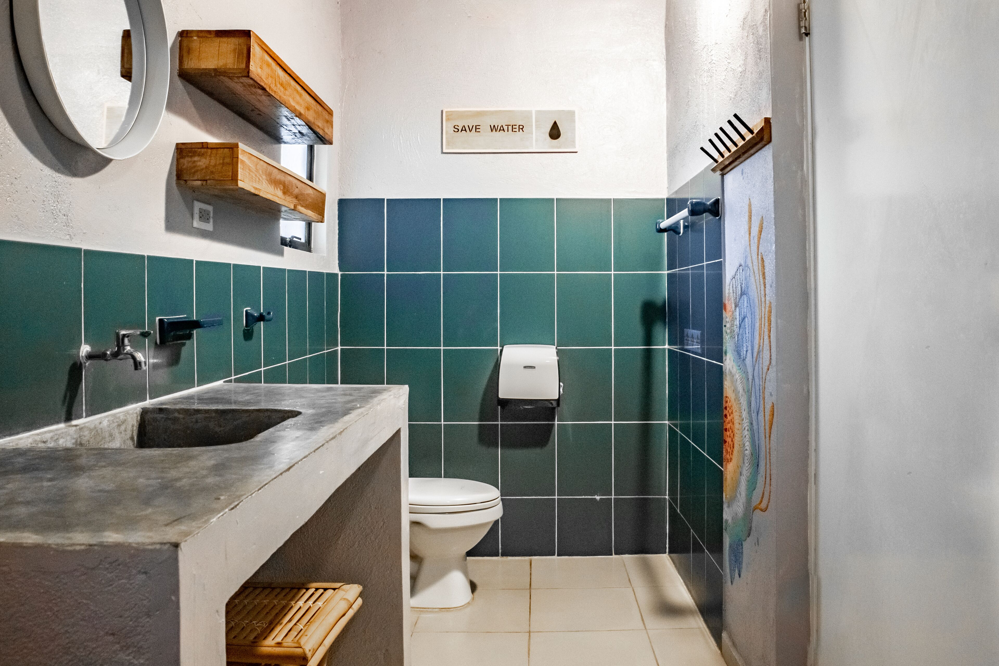 Un baño con lavamanos, inodoro y un cartel que dice 'AHORRA AGUA'.