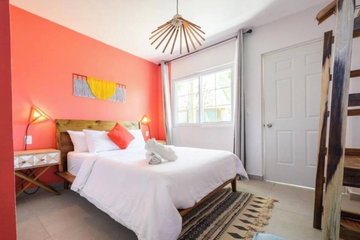 A bedroom with a bed, bedside tables, a window, and a door.