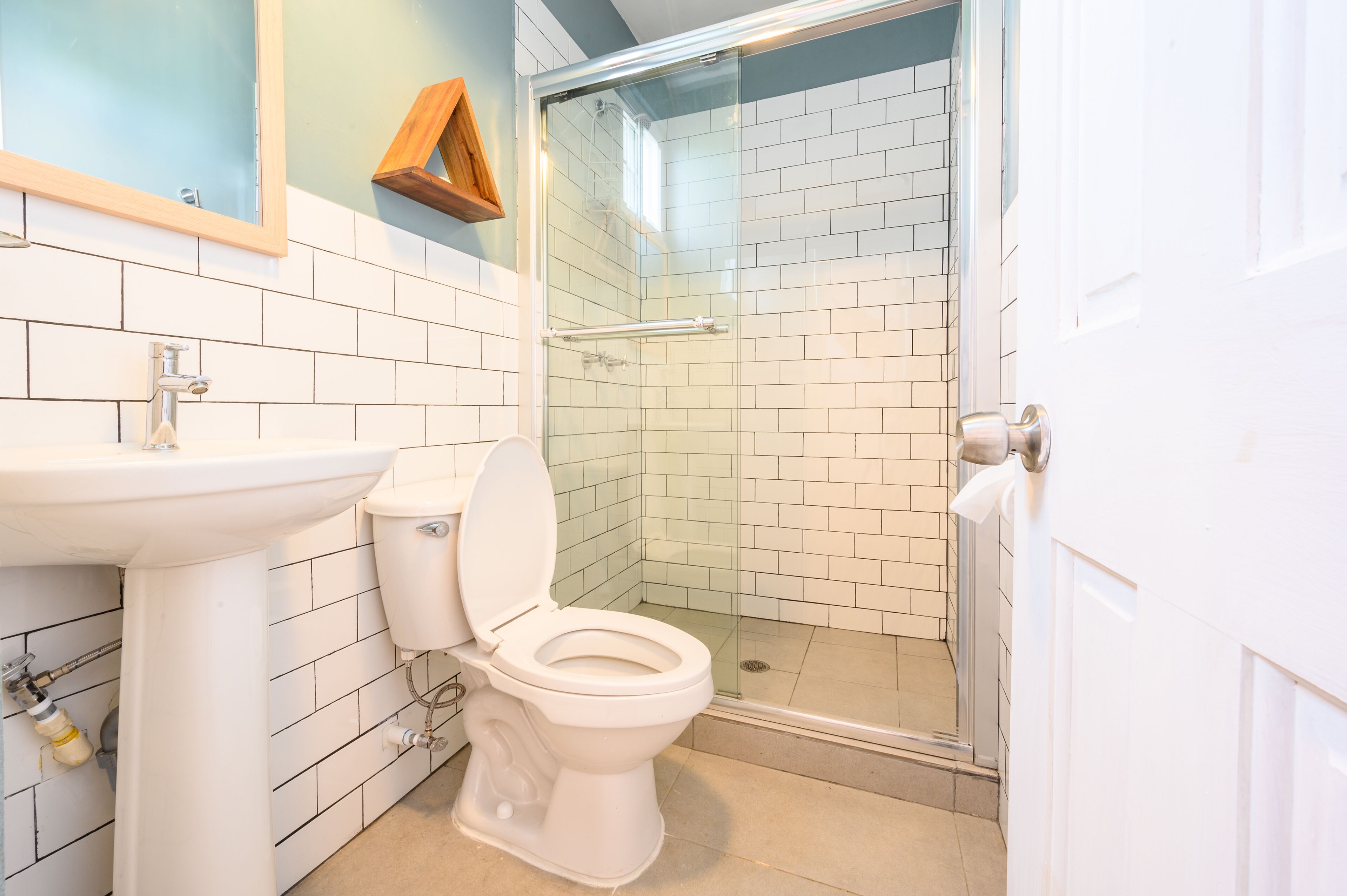 Un baño con lavamanos blanco, inodoro y ducha con mampara de vidrio.