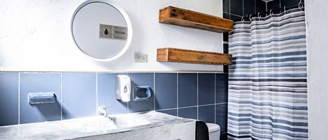 A bathroom with a white sink, a mirror, a toilet, and a shower curtain.