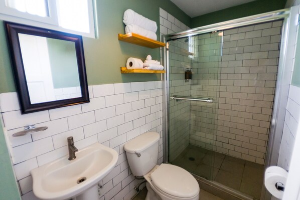 Un baño con lavamanos, inodoro y ducha con mampara de vidrio.