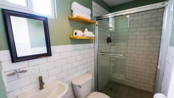 A bathroom with a toilet, sink, and glass shower enclosure.