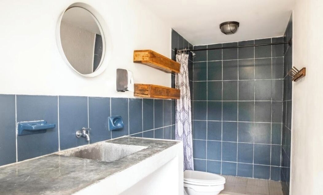 Une salle de bain avec un lavabo en marbre, un miroir, un porte-serviettes et une douche aux carreaux bleu foncé.