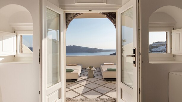 An open doorway leading to a balcony with a view of the sea and a distant island. - Canaves Oia Suites - Small Luxury Hotels of the World (Santorini)