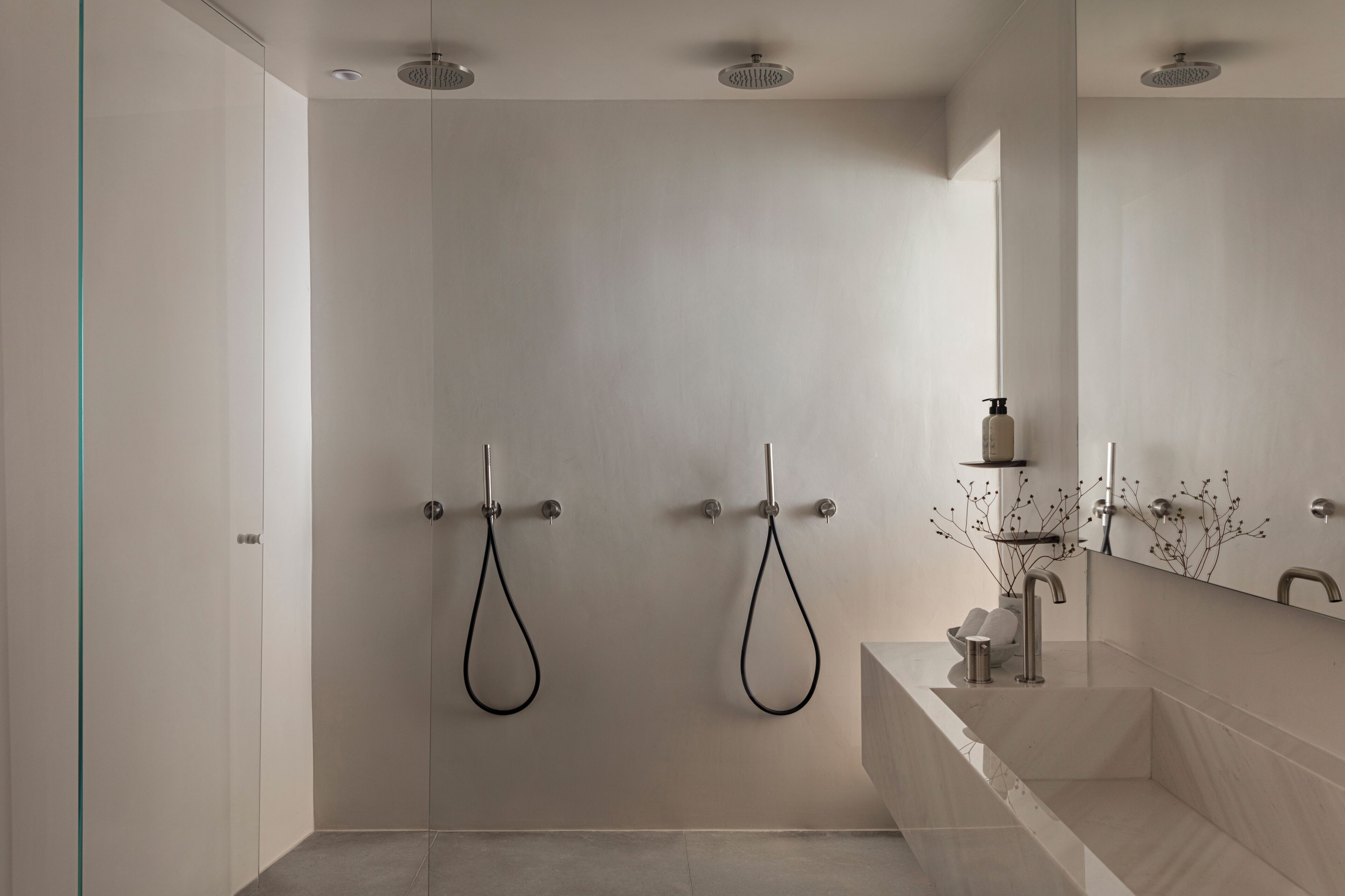 Une salle de bain moderne avec une douche à l’italienne, un grand miroir et un lavabo au design épuré.