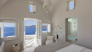 Un dormitorio con una cama grande, vista al mar y un baño con ducha.