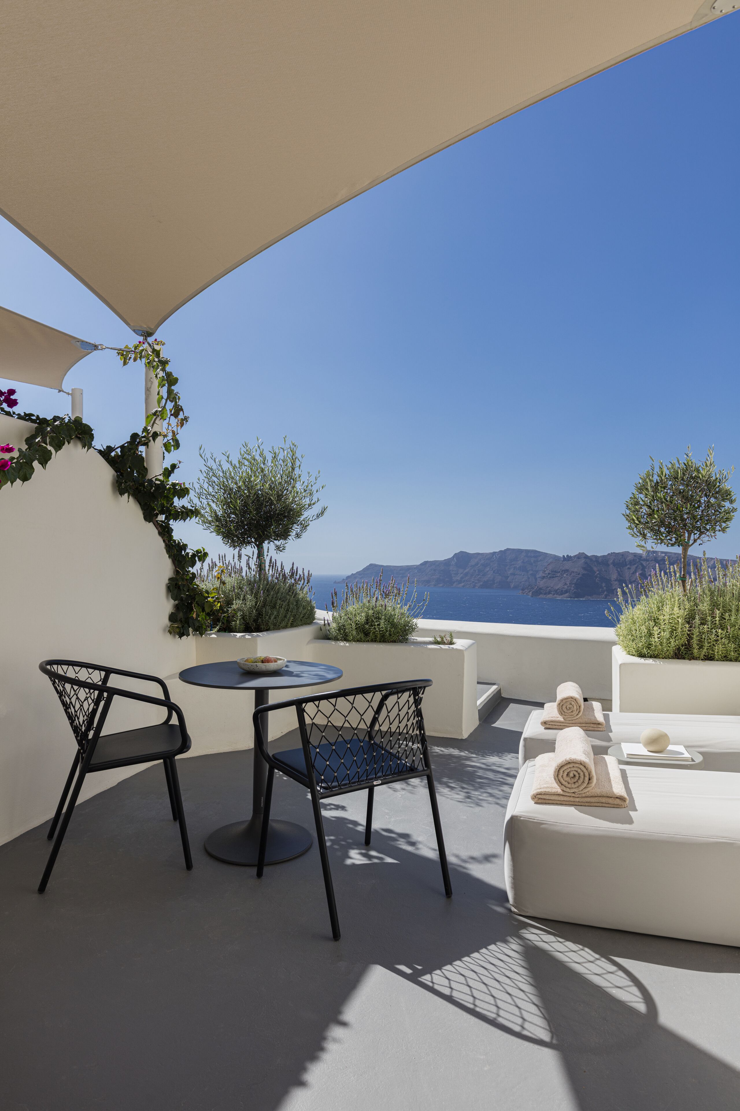 A terrace with a table and chairs, a sofa, and a view of the sea and mountains.