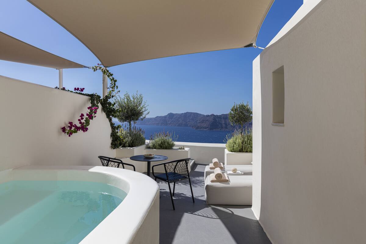 A balcony with a hot tub, seating, and a view of the sea.