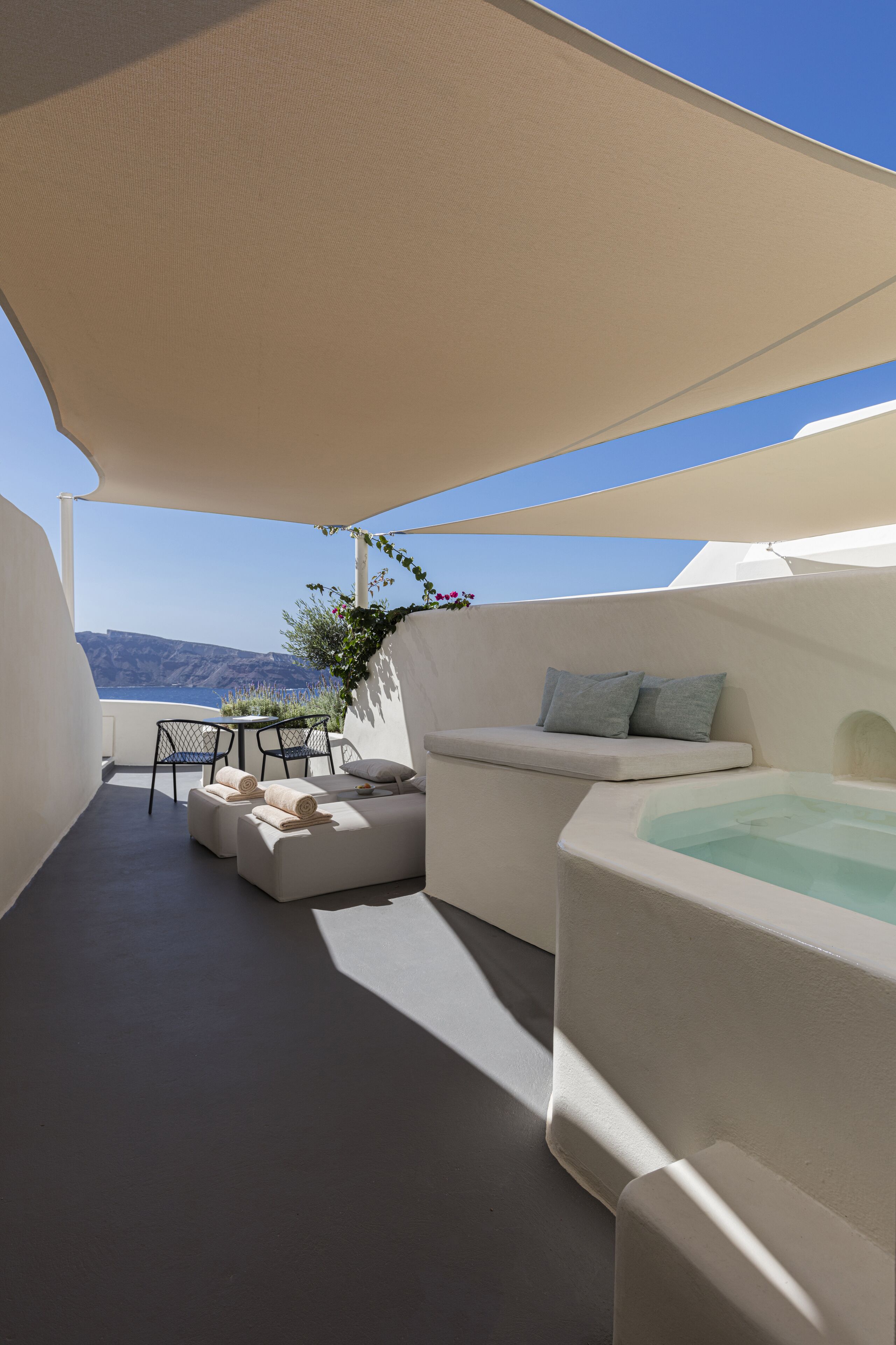 A rooftop terrace with a seating area, a table, and a hot tub.