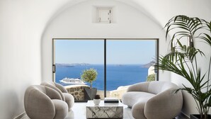 Un salón moderno con un amplio ventanal corredera que da a un balcón con vista al mar.