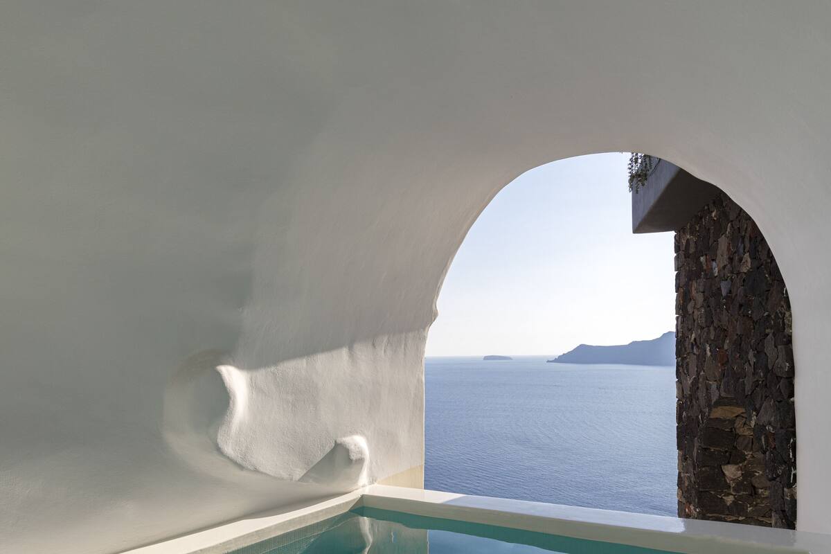 A swimming pool with a view of the sea and a stone wall.