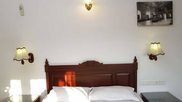 Una camera d'albergo con un letto in legno, due comodini, una lampada a parete e un quadro appeso al muro.