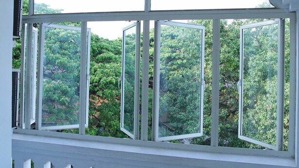 Habitación con un amplio ventanal arqueado que ofrece vistas a un área boscosa.
