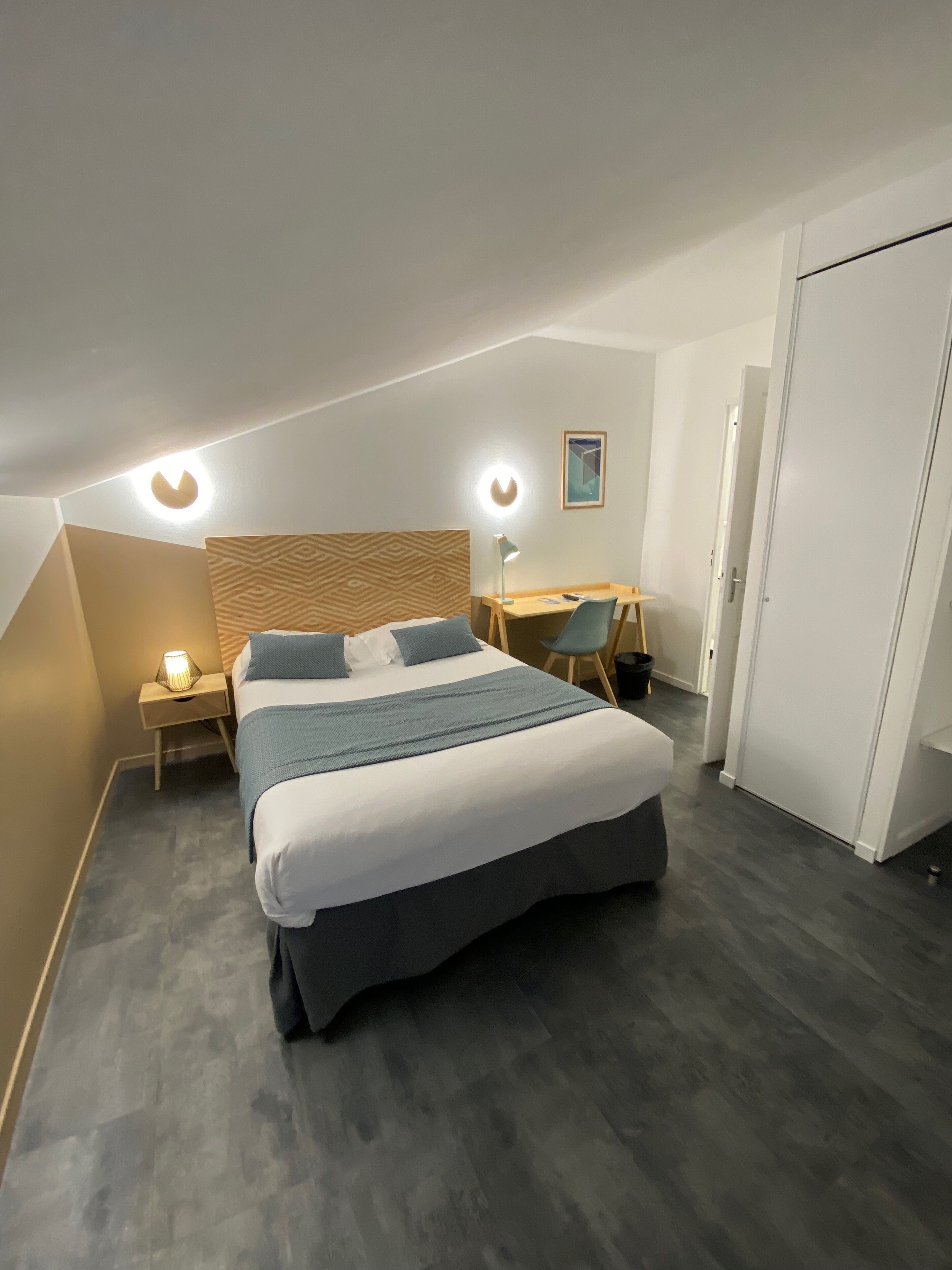 A modern bedroom with a large bed, bedside tables, a desk, and a wardrobe.