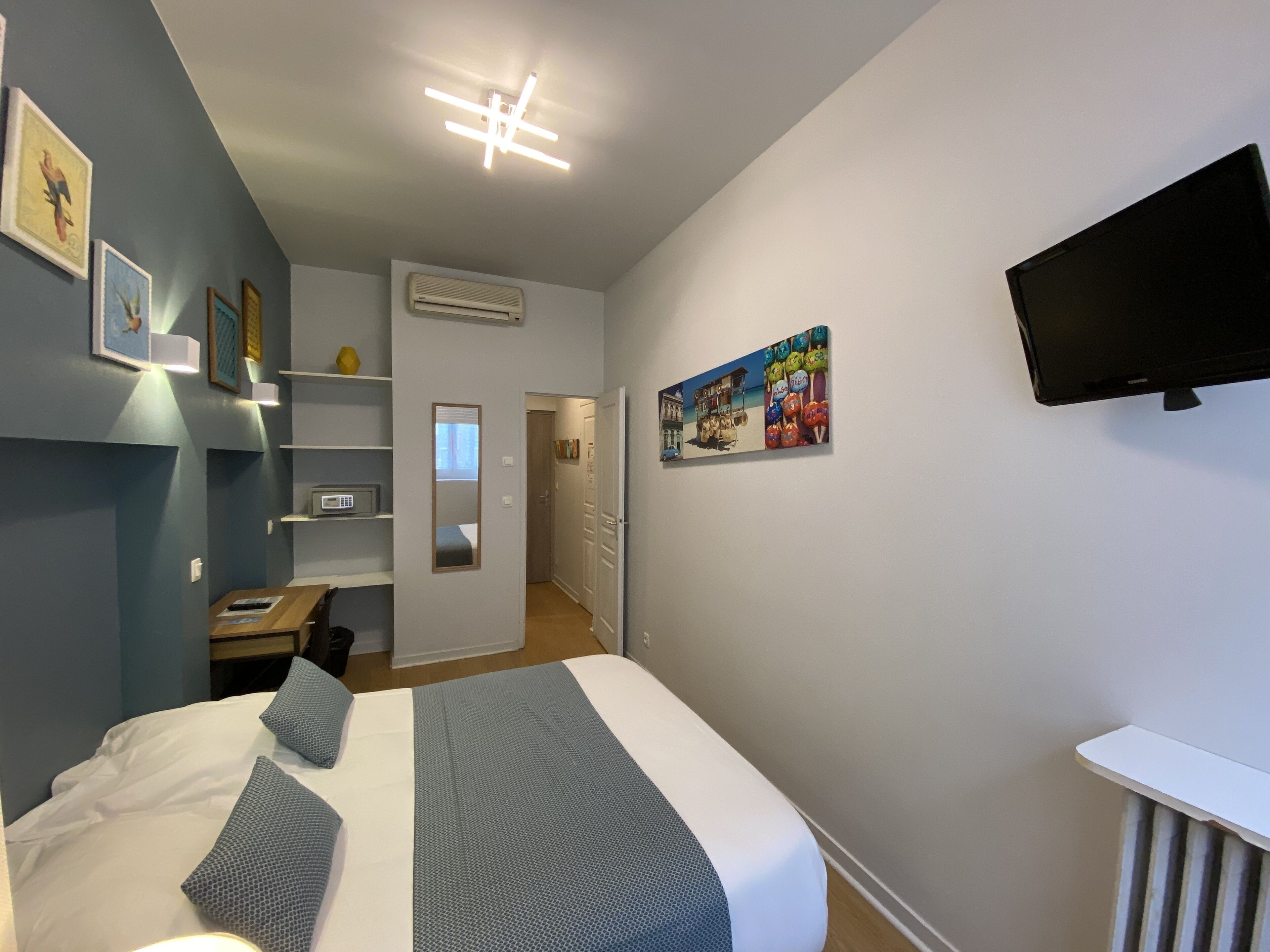 A bedroom with a bed, a TV mounted on the wall, and a door leading to a bathroom.