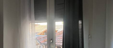 Una habitación con ventana, radiador y cortina.