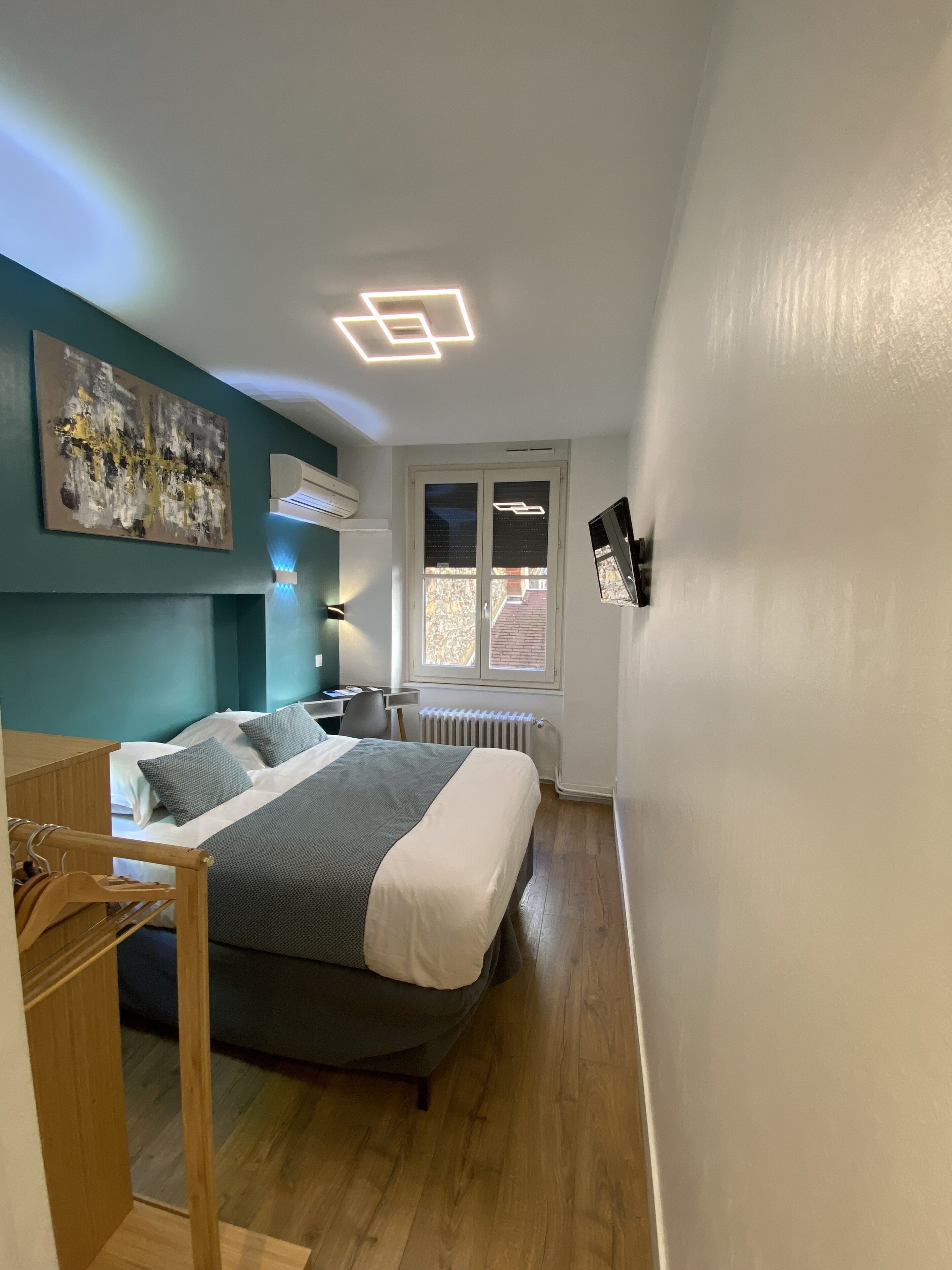 A bedroom with a bed, a desk, and a radiator.