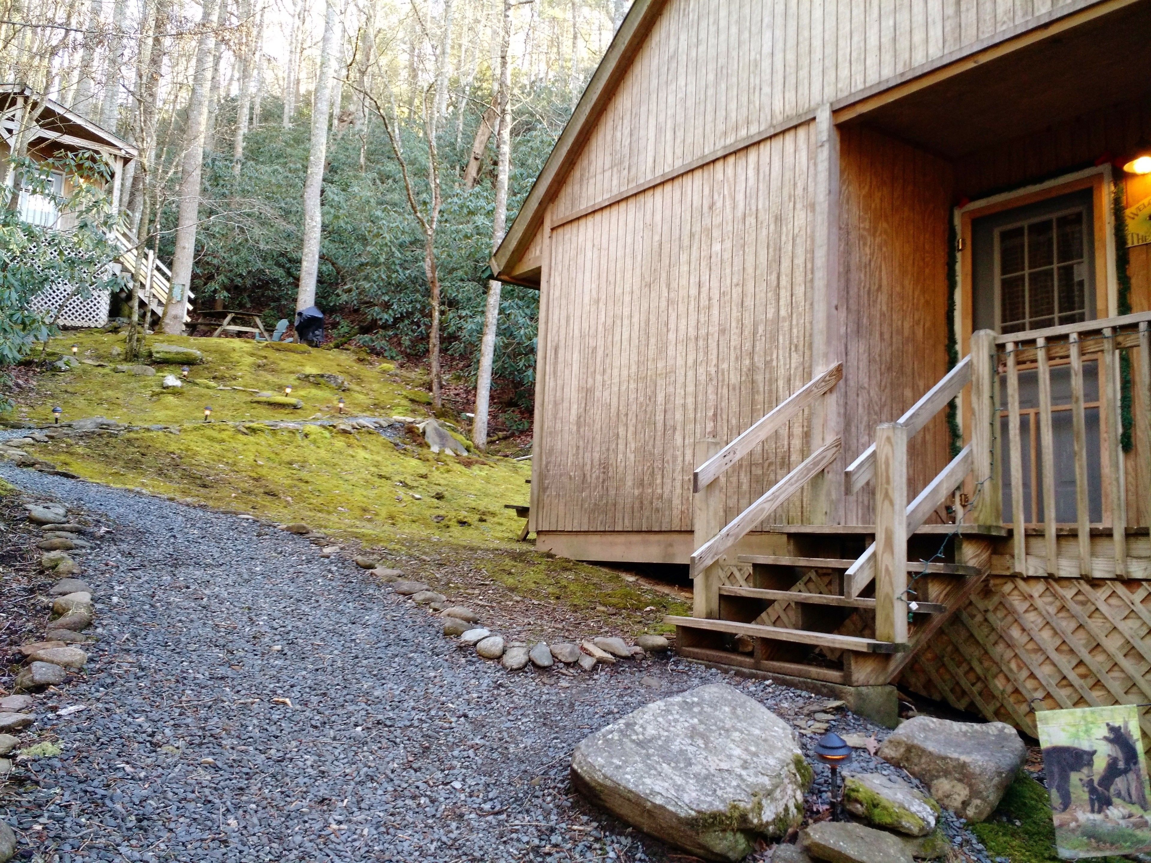 A wooden cabin with a gravel path leading to a wooden staircase.