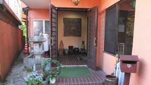 A courtyard with a stone lantern, potted plants, and a tiled entrance. - Turtle Inn Nikko (Nikko)