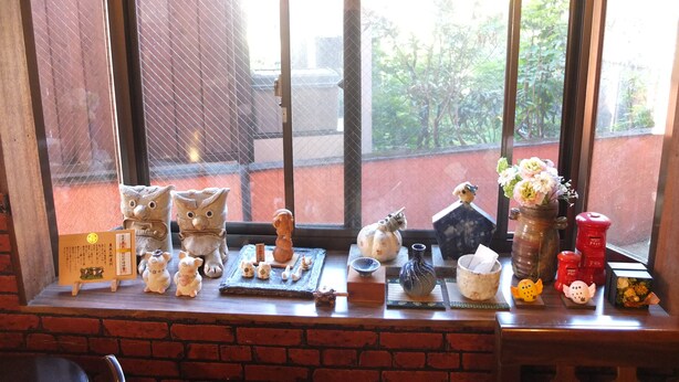 A window display with various figurines and decorative items on a shelf. - Turtle Inn Nikko (Nikko)