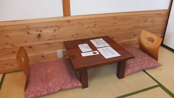 Een traditionele Japanse kamer met tatami vloeren, een lage houten tafel met papieren en twee houten stoelen met kussens.