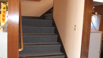 Una escalera con alfombra, barandillas de madera y pared blanca.