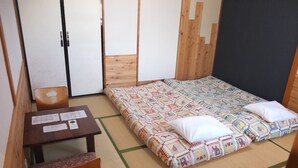 A room with a bed, a small table with a chair, and a wooden wardrobe. - Turtle Inn Nikko (Nikko)