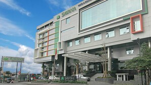 A modern hotel building with a prominent Savana logo, large windows, and a covered entrance area.