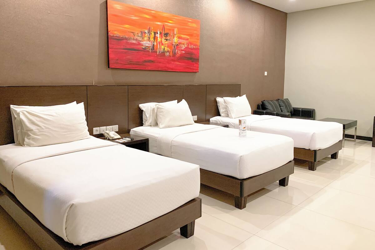 A hotel room with two beds, a desk, and a painting on the wall.