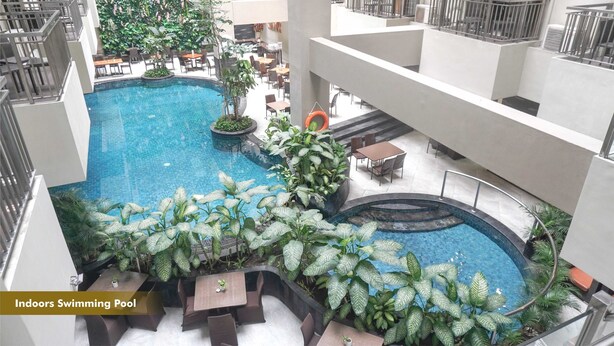 An indoor swimming pool with surrounding seating and plants.