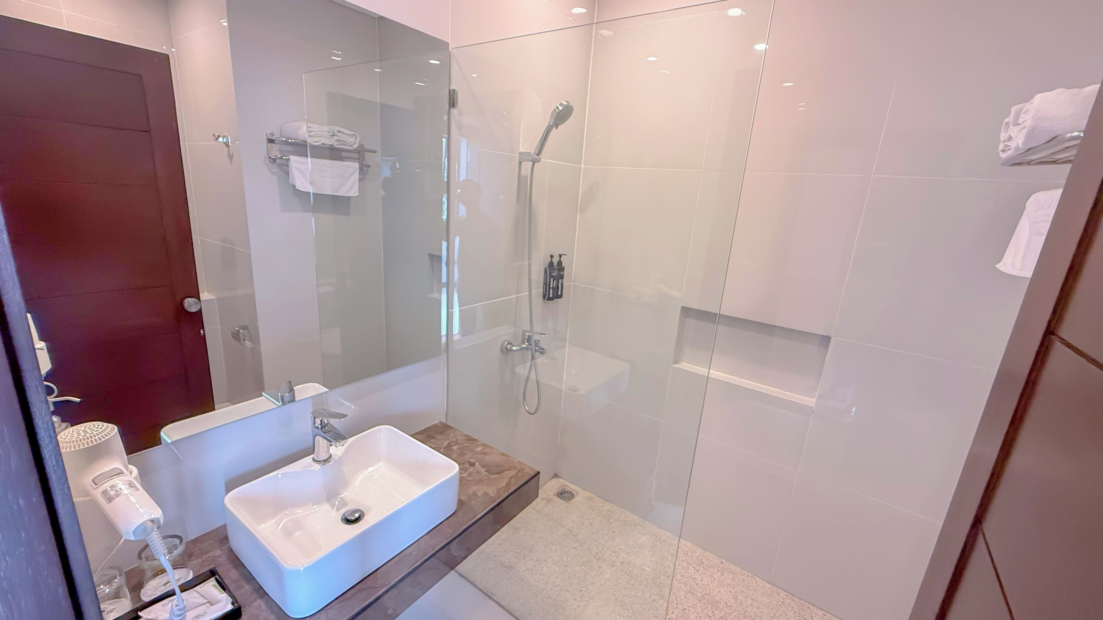 A modern bathroom with a glass-enclosed shower, a white sink, and a towel rack.