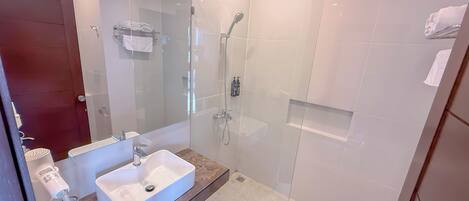 A modern bathroom with a glass-enclosed shower, a white sink, and a towel rack.