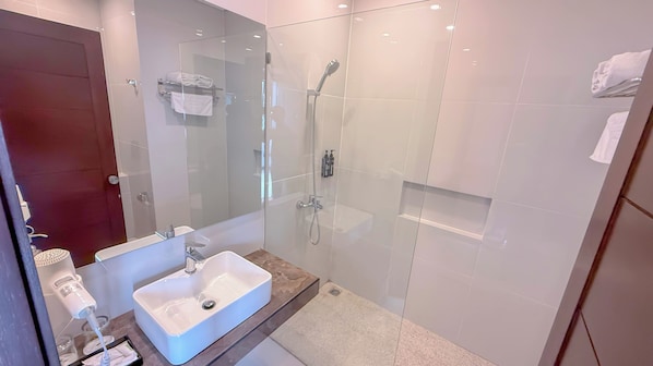 A modern bathroom with a glass-enclosed shower, a white sink, and a towel rack.