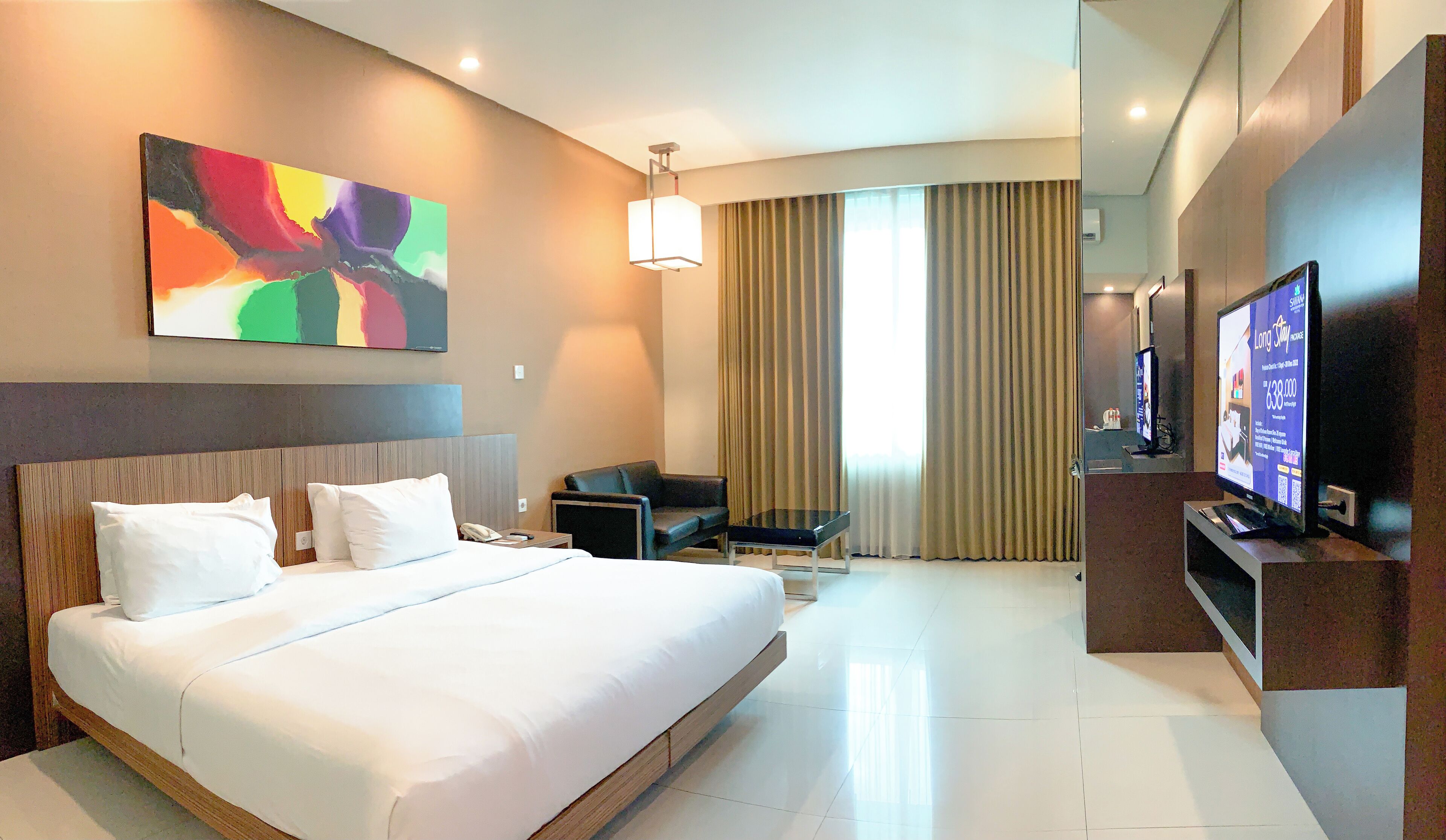 A hotel room with a large bed, a desk, a chair, a television, and a painting on the wall.