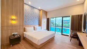 A modern hotel room with a large bed, a desk, a small table, and a view of a swimming pool.