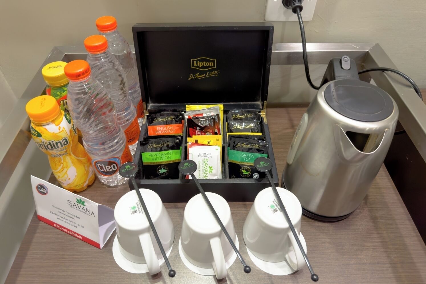 A minibar with various beverages, including water, juice, and tea, and a coffee maker.
