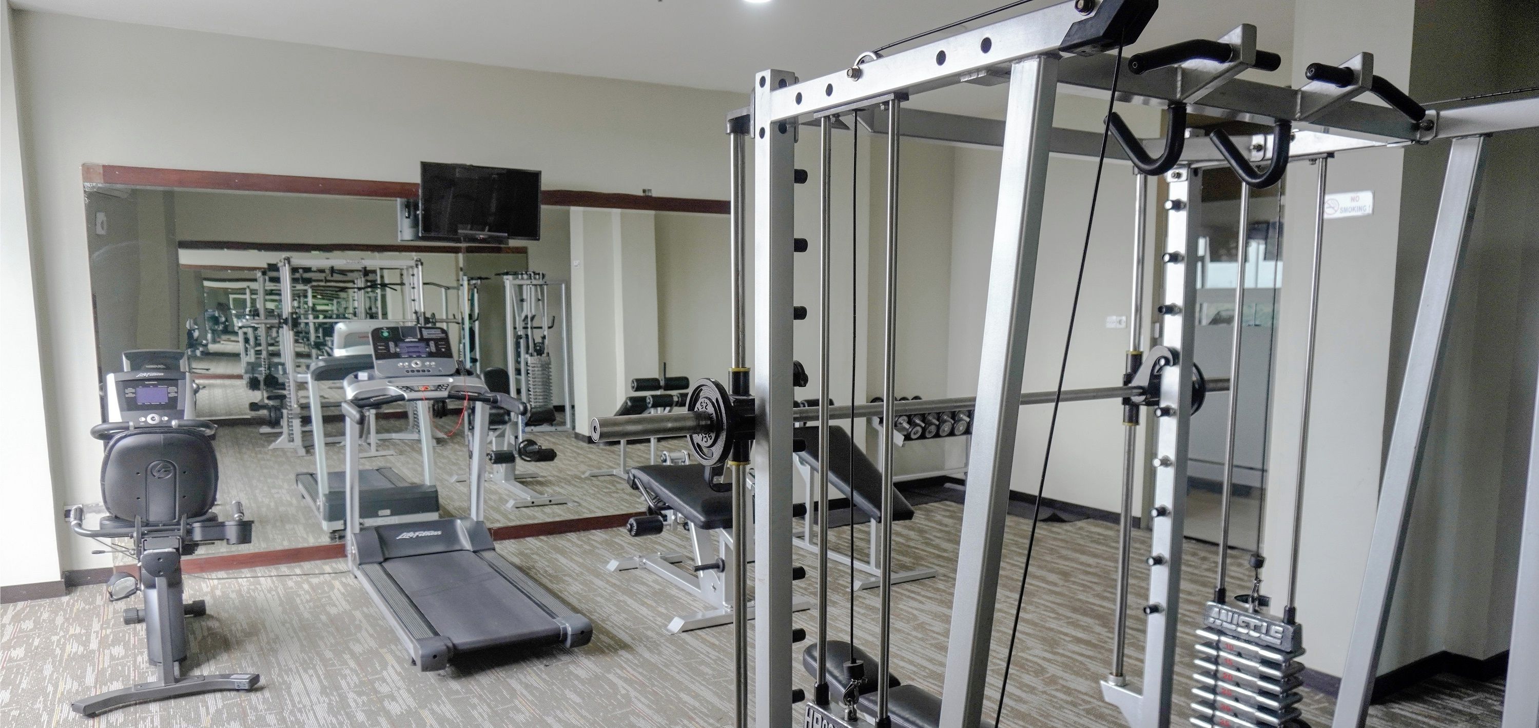 A fitness center with treadmills, weight machines, and a mirrored wall.