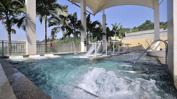 Un área de hidromasaje con dosel, palmeras y una piscina.