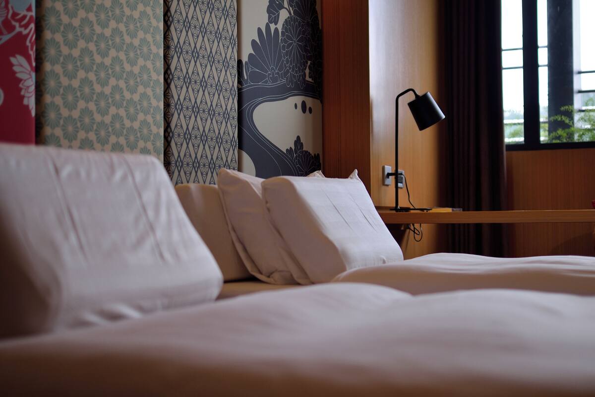 A neatly made bed with white linens in a hotel room.