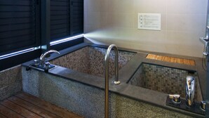 Ein modernes Badezimmer mit Holzboden, einer großen Badewanne und einer gefliesten Wand.