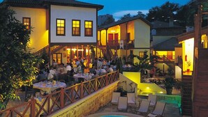 A poolside area with a pool, outdoor seating, and a building with multiple windows. - Tekeli Konakları (Antalya)