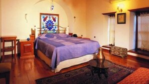 A bedroom with a bed, a nightstand, a lamp, a decorative vase, and a rug. - Tekeli Konakları (Antalya)