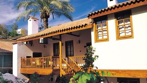 A two-story building with a balcony, a palm tree, and flowering plants. - Tekeli Konakları (Antalya)