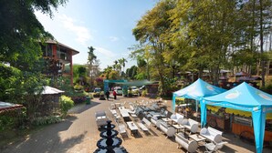 A courtyard with outdoor seating, a fountain, and a blue tent. - Royal Caravan Hotel Trawas (Trawas)