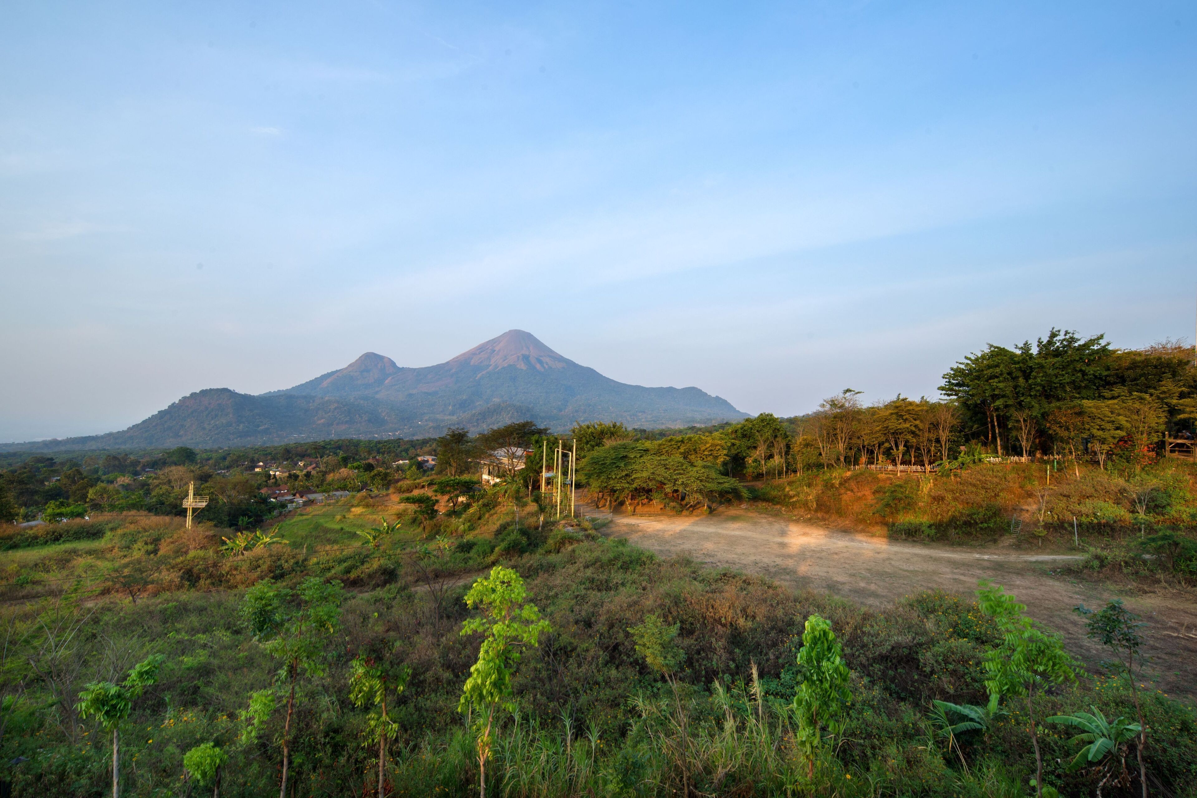 Un paisaje rural con una montaña al fondo, un sendero de tierra y vegetación escasa.