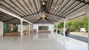 A spacious indoor area with a high ceiling, a central chandelier, and a banner on the wall. - Royal Caravan Hotel Trawas (Trawas)