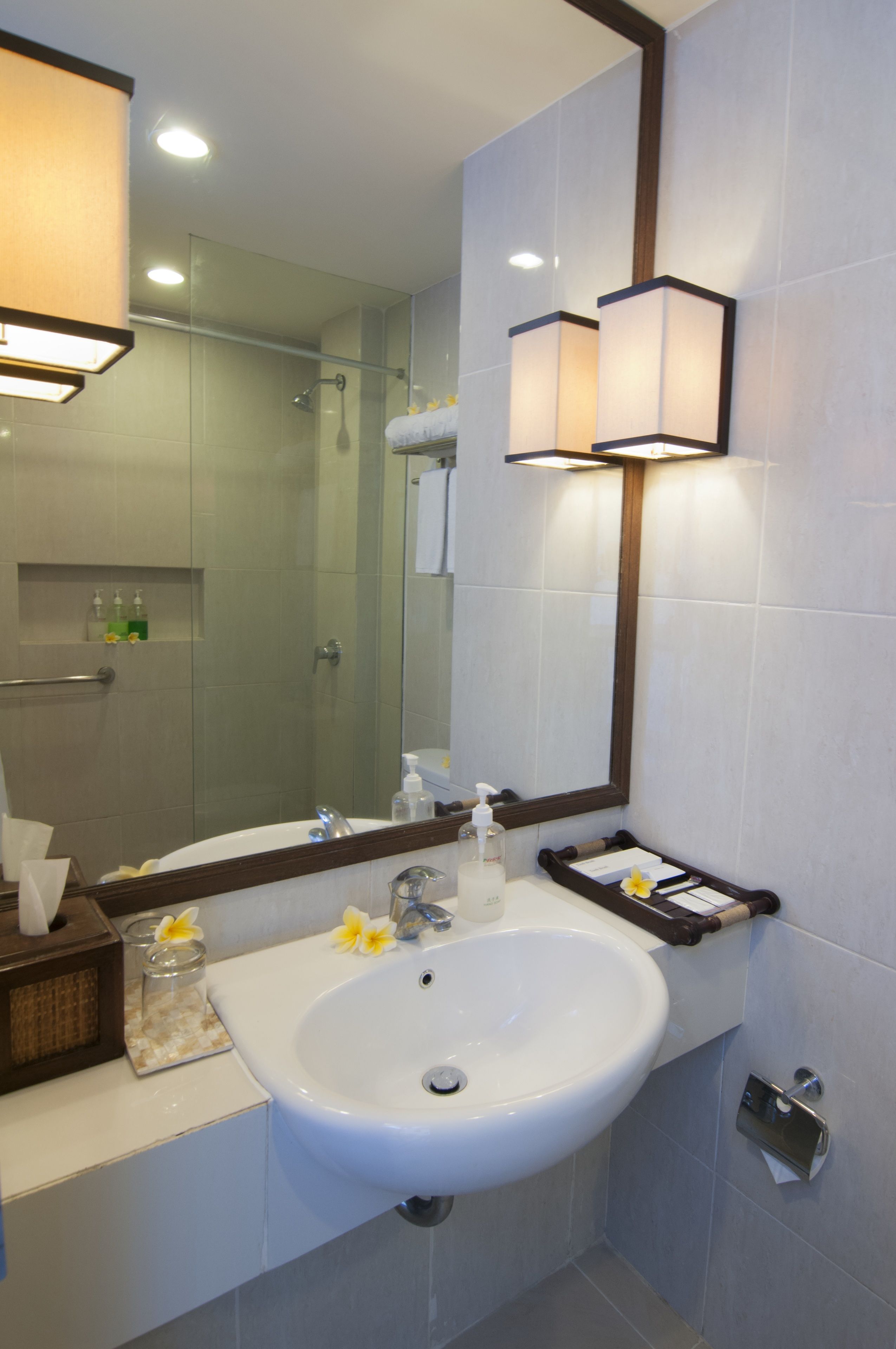 A modern bathroom with a large mirror, a white sink, and a glass shower enclosure.