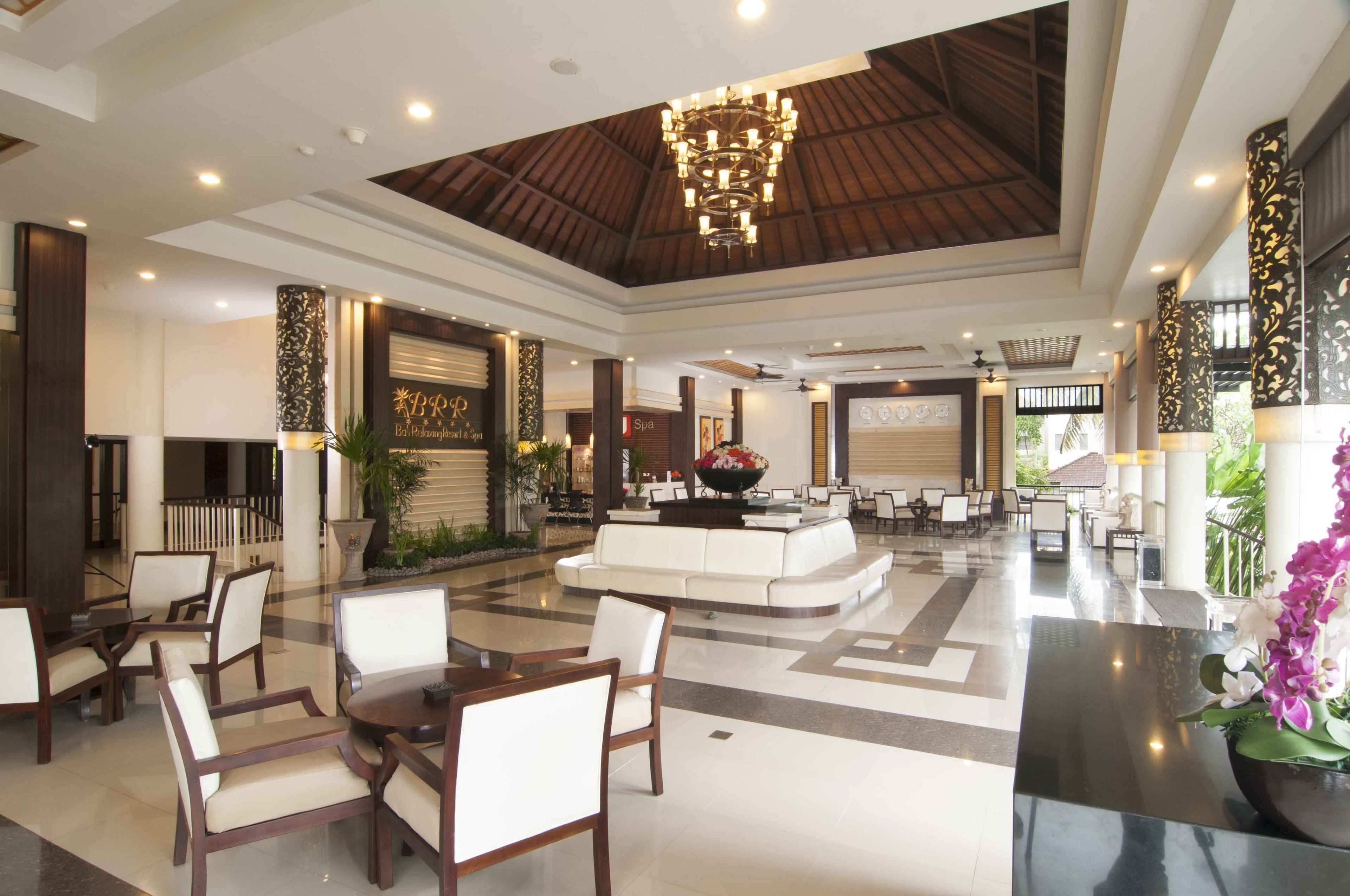 A spacious lobby with a central seating area, multiple tables, and a large chandelier.